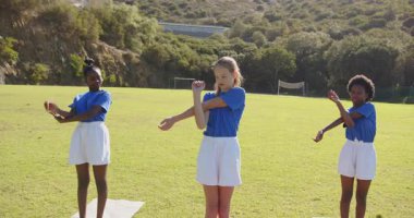 Okulda, kızlar dışarıda beden eğitimi dersinde yoga minderleri esnetiyorlar. Fitness, egzersiz, açık hava, çocukluk, sağlık, aktivite