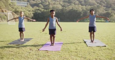 Paspaslar üzerinde yoga çalışması, okul sahasında gerinen üç çocuk. Çocuklar, egzersiz, sağlık, spor, esneklik, farkındalık