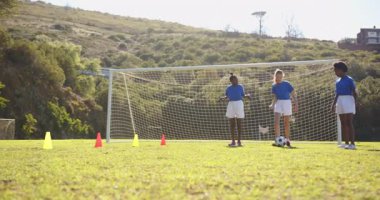 Okul sahasında futbol oynamak, üniformalı kızlar koşmak ve topa vurmak. Spor, takım çalışması, aktivite, açık hava, fitness, çocukluk