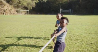 Playing tug-of-war, kids enjoying outdoor activity on school field with friends. fun, team-building, exercise, children, sports, competition