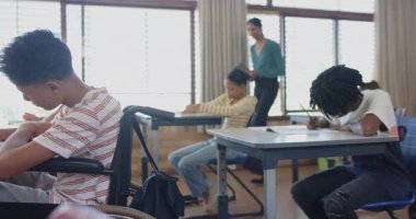 Okulda, sınıfta tekerlekli sandalyedeki çocuk not defteriyle yazı yazıyordu. Eğitim, engellilik, öğrenme, kapsama, çocukluk, erişilebilirlik