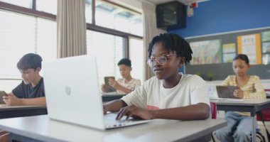 Okulda, sınıfta dizüstü bilgisayar kullanan, işine odaklanan bir çocuk. Eğitim, teknoloji, öğrenim, öğrenim, dijital, öğrenci