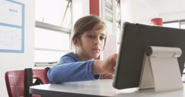 Okulda, sınıfta tablet kullanan bir çocuk, öğrenmeye odaklanmış. Eğitim, teknoloji, öğrenim, çocukluk, dijital, öğrenci