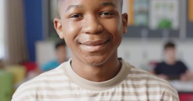 Sınıfta gülümseyen çocuk, arka planda sınıf arkadaşlarıyla eğleniyor. Çocuklar, eğitim, mutluluk, öğrenme, arkadaşlık, eğlence