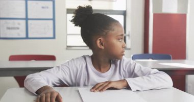 Okulda, sınıfta masa başında otururken yüzünü ellerle örten bir öğrenci. Eğitim, çocukluk, stres, akademik, öğrenim, bunalmış