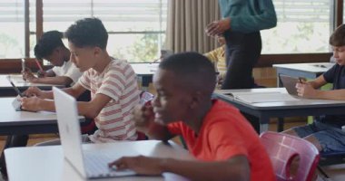 Okulda öğrenciler, öğretmenlerinin yardımıyla sınıfta dizüstü bilgisayar ve tablet kullanıyorlar. Eğitim, teknoloji, öğrenme, dijital, akademik