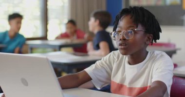 Okulda, bilgisayar kullanan ve sınıfta dikkatle dinleyen bir öğrenci. Eğitim, öğrenme, teknoloji, öğrenim, odaklanma, dikkat