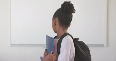 Sırtında not defteri ve sırt çantası olan gülümseyen Afrikalı Amerikalı kız okula gitmeye hazır. Eğitim, okula dönüş, öğrenme, öğrenci, akademik, öğrenim