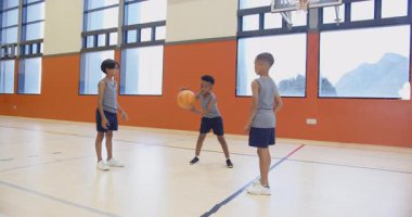 Okulun spor salonunda basketbol oynamak, pas veren ve eğlenen üç çocuk. Spor, takım çalışması, eğlence, gençlik, spor salonu, egzersiz