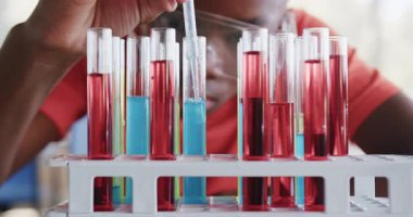 Okulda, güvenlik gözlüğü takan bir öğrenci fen dersinde test tüplerini inceliyor. eğitim, deney, laboratuvar, kimya, araştırma, öğrenme