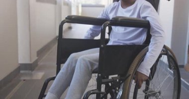 Okulda tekerlekli sandalyede gülümseyen Afrikalı Amerikalı kız, koridorda eğleniyor. Mutluluk, gençlik, kapsama, erişilebilirlik, eğitim, çeşitlilik