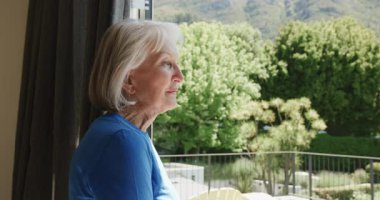 Yaşlı kadın pencereden dışarı dikkatlice bakıyor. Huzurlu doğa manzarasının tadını çıkarıyor. Evinde, kopyalama alanının. Düşünce, sükunet, yansıma, olgun, huzur, rahatlama.