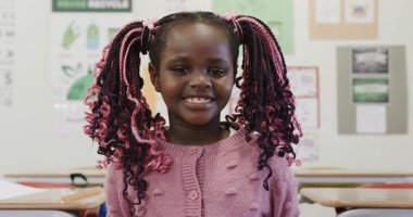 Sınıfta renkli örgüleriyle gülümseyen Afrikalı Amerikalı kız okulda kendini mutlu hissediyordu. Eğitim, mutluluk, öğrenme, çeşitlilik, çocukluk, saç stili