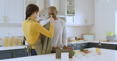 Mutfakta birlikte yemek pişiren, gülümseyen ve evde yemek tarifi için tablet kullanan çok ırklı bir çift. ev hayatı, teknoloji, mutluluk, takım çalışması, aşçılık, yaşam tarzı