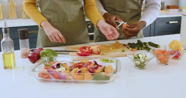 Çok ırklı bir çift mutfakta birlikte taze sebzeler hazırlıyor, evde ve evde yemek pişirmenin keyfini çıkarıyorlar. Mutfak, yemek hazırlama, sağlıklı beslenme, takım çalışması, yaşam tarzı, yerli