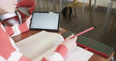 Sınıfta tablet kullanan ve notlar yazan küçük bir kız. Öğrenme, okulda, kopyalama alanına odaklanıyor. Eğitim, teknoloji, dijital, öğrenim, akademisyenler, okul