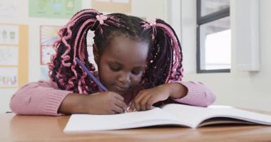 Okulda, masa başında kalemle hayal kuran genç bir kız, düşünceli görünüyor. Çocukluk, eğitim, öğrenme, düşünme, düşünme, yaratıcılık