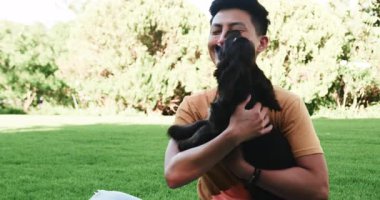 Asyalı bir adam parkta köpekle oynuyor, açık havada güneşli bir günün tadını çıkarıyor. eğlence, arkadaşlık, evcil hayvan, aktivite, dinlenme, gün ışığı