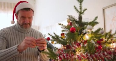 Son sınıf öğrencisi Noel Baba şapkası takıyor Noel ağacını süslüyor, neşeli hissediyor. Tatiller, şenlik, kutlama, gelenek, yaşlılar, dekorasyon