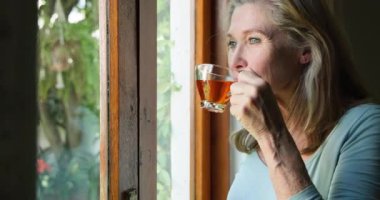 Gülümseyen son sınıf öğrencisi kadın evde sabah kahvesinin keyfini çıkarıyor. Rahatlama, sabah rutini, yaşam tarzı, eğlence, mutluluk, olgun yetişkinler.