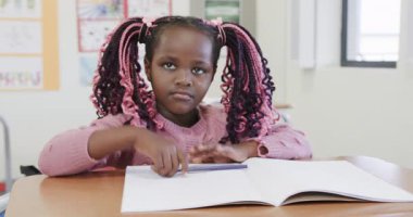 Sınıfta, Afrika kökenli Amerikalı kız el kaldırıyor, okulda öğrenme aktivitesiyle meşgul. Eğitim, okul, kız, merak, katılım, coşku