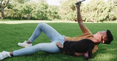 Parkta güneşli bir günün tadını çıkaran Asyalı bir adam, mutlu yavru köpekle oynuyor. Açık hava, doğa, eğlence, mutluluk, evcil hayvan, köpek