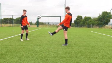 Genç futbolcular sahada antrenman yapıyor, top kontrolü ve takım çalışmasına odaklanıyor. eğitim, spor, gençlik, sporcular