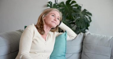 Gülümseyen son sınıf öğrencisi kadın evdeki rahat koltukta kahvenin tadını çıkarıyor. Yaşlılık, rahatlama, yaşam tarzı, rahatlık, sıcaklık, rahatlık.