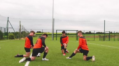 Futbolcular sahada diz çöküp antrenman sırasında strateji tartışıyorlar. Spor, takım çalışması, eğitim, taktik, işbirliği, birlik