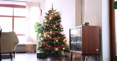 Evdeki rahat oturma odasında ışıkları ve süslemeleri olan şenlikli Noel ağacı. tatil, dekorasyon, kapalı alan, kutlama, mevsimlik