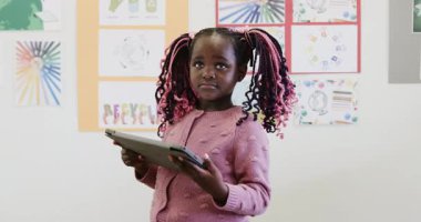 Okulda, sınıfta tablet kullanan genç bir kız, odaklanarak öğreniyor. Eğitim, teknoloji, dijital, çocukluk