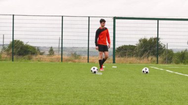 Turuncu formalı futbolcu sahada antrenman yapıyor, tekmeye hazırlanıyor. Sporcu, spor, antrenman, yarışma, egzersiz, eğitim