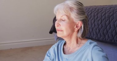 Evde oturan, kıdemli bir kadın oturma odasında düşünceli ve mutlu görünüyor. Yaşlılık, rahatlama, tefekkür, yaşam tarzı, dinginlik, rahatlık.