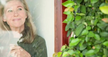 Gülümseyen son sınıf öğrencisi kadın, evinde yemyeşil çayla çevrili olarak çayın keyfini çıkarıyor. Yaşlılık, rahatlama, sükunet, doğa, sükunet, rahatlık.