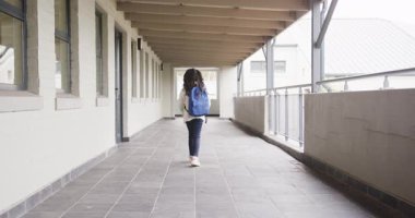 Okul koridorunda mavi sırt çantasıyla yürüyen bir kız. Kopya alanı. kız, eğitim, öğrenim, akademik, gençlik, öğrenci