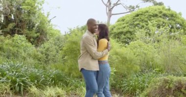 Birlikte dans ediyorlar, yemyeşil bahçede çok ırklı çiftler, doğanın tadını çıkarıyorlar. Romantizm, eğlence, birliktelik, açık hava, mutluluk.