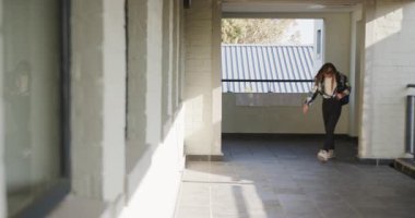 Okul koridorunda yürüyen, sırt çantasını ayarlayan, göreve odaklanan, kopyalama alanı olan genç bir kız. Eğitim, genç kız hayatı, öğrenim, kampüs, akademik, seyahat