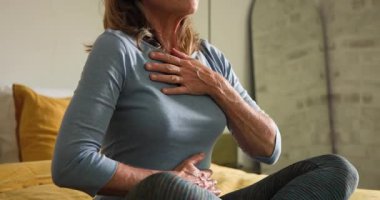 Yaşlı kadın kulaklıkla meditasyon yapıyor, evde yatakta dinleniyor. Meditasyon, rahatlama, farkındalık, sağIık, sükunet, huzur