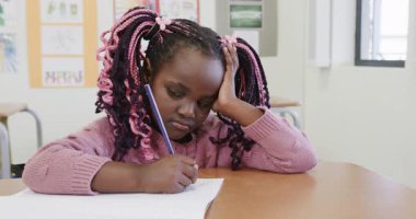 Sınıfta, genç bir kız okulda, derin düşüncelerle, not defterine yazmaya konsantre oluyor. Eğitim, konsantrasyon, öğrenme, öğrenme, okul, çocukluk