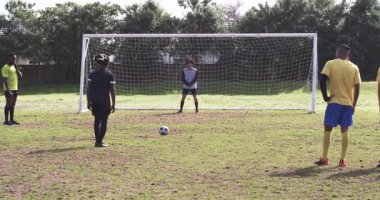 Futbolcular golü güneşli sahada takla atarak kutluyorlar, heyecan gösteriyorlar. Spor, takım çalışması, kutlama, rekabet, zafer, mutluluk