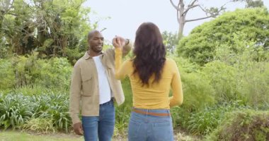 Çeşitli çok ırklı çiftler yemyeşil parkta neşeyle kucaklaşıp birlikteliklerini kutluyorlar. Romantizm, mutluluk, aşk, açık hava, kutlama, birlik