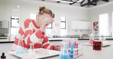 Bilim deneyi yapıyor, laboratuardaki genç kız güvenlik gözlüğü takıyor. Eğitim, kimya, öğrenme, sınıf