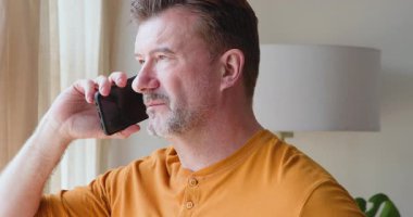 Son sınıf öğrencisi akıllı telefondan konuşuyor, günlük turuncu gömlek giyiyor. Teknoloji, iletişim, yaşlılık, rahatlama, yaşam tarzı, rahatlık