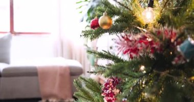 Noel ağacını renkli süslemeler ve evde yanıp sönen ışıklarla süslemek. bayram, şenlik, dekorasyon, aile, gelenek, kutlama