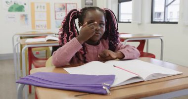 Sınıfta, örgülü genç bir kız el çırpıyor, okulda okul aktivitelerinden keyif alıyor. Eğitim, öğrenme, çocukluk, yaratıcılık, eğlence, sınıf etkinliği