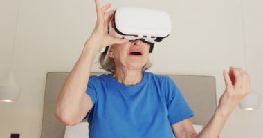 Kıdemli kadın evde deneyim kazanmak için sanal gerçeklik kulaklığı kullanıyor. Teknoloji, eğlence, yenilik, yaşam tarzı, yaşlılar, fütüristik