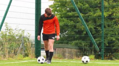 Turuncu formalı futbolcu sahada yürüyor, odaklanmış ve kararlı. Futbol, atlet, spor, rekabetçi, konsantrasyon, takım