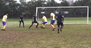 Futbolcular yoğun bir şekilde sahada yarışıyor, gol savunma stratejisine odaklanıyor. rekabet, takım çalışması, sporcular, sportmenlik, aksiyon, açık hava