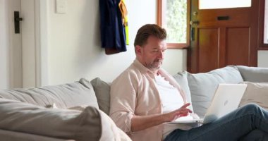 Son sınıf öğrencisi evde dizüstü bilgisayar kullanarak kanepede dinleniyor, boş vakitlerin tadını çıkarıyor. Yaşlılar, rahatlama, teknoloji, dijital, yaşam tarzı, konfor