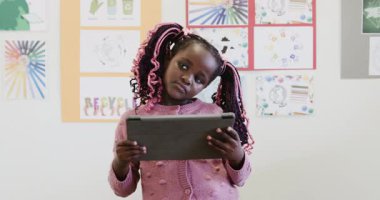 Sınıfta, elinde tablet olan genç bir kız, eğitimsel içeriği incelikle, okulda keşfediyor. Teknoloji, öğrenme, dijital, okul, bilgi